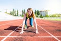 A young woman in the starting position for running on a sports track Royalty Free Stock Photo