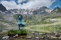 Young woman stays in one leg yoga position against the turquoise lake in the mountains Royalty Free Stock Photo