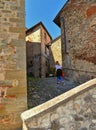 Young woman on the steps of narrow street in old historic alley in the medieval village of Anghiari near city of Arezzo in Tuscany