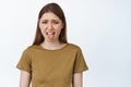 Young woman stick tongue from dislike, disgusted with bad taste, smth awful or disgusting, standing over white Royalty Free Stock Photo