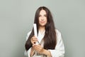 Young woman straighten her hair with straightener on white background. Haircare concept Royalty Free Stock Photo