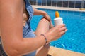 Young woman in straw hat applying sun protection cream suntan sunscreen lotion near swimming pool at resort Royalty Free Stock Photo