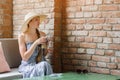 Young woman in straw hat and long dress drinking beverage against brick wall Royalty Free Stock Photo