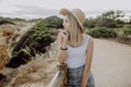 Young beautiful woman in straw hat standing on the view point of seacost with stone beach on background Royalty Free Stock Photo