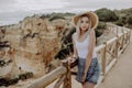 Young beautiful woman in straw hat standing on the view point of seacost with stone beach on background Royalty Free Stock Photo