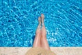 Young woman in straw hat sunbathing sitting on the edge of swimming pool with legs in water Top view Royalty Free Stock Photo