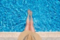 Young woman in straw hat sunbathing sitting on the edge of swimming pool with legs in water Top view Royalty Free Stock Photo