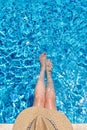 Young woman in straw hat sunbathing sitting on the edge of swimming pool with legs in water Top view Royalty Free Stock Photo