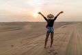 Young sexy woman with straw hat walking barefoot on desert dunes at sunset Royalty Free Stock Photo