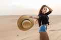 Young sexy woman with straw hat walking barefoot on desert dunes at sunset Royalty Free Stock Photo