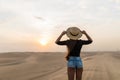 Young sexy woman with straw hat walking barefoot on desert dunes at sunset Royalty Free Stock Photo