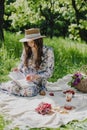 Young woman in straw hat wearing summer dress reading a book while relaxing in the park. Royalty Free Stock Photo