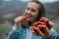 Young woman with strawberries in the nature on a background of m Royalty Free Stock Photo