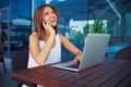 Young woman in street cafÃÂ© using her laptop and talking on mobile phone Royalty Free Stock Photo