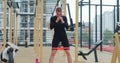 Young woman strengthening legs with fitness band on sports ground. Physical training. Healthy lifestyle. Outdoor