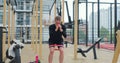 Young woman strengthening legs with fitness band on sports ground. Physical training. Healthy lifestyle. Outdoor