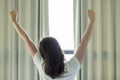 Young woman stretching in the morning and open curtains, early wake up concept.