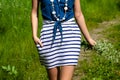 Young woman in striped clothes walks in nature with bouquet of flowers. Summer vacation on a sunny day Royalty Free Stock Photo
