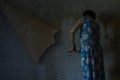 A young woman stripping wallpaper in a house