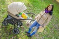 Young woman with a stroller in a city park. Happy mother with a baby stroller Royalty Free Stock Photo