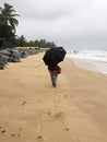 A young woman strolling on the beaches of Kundapura under an umbrella Royalty Free Stock Photo