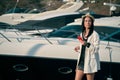 young woman strolling through a marina, with smartphone and boats behind