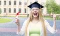 Young woman student in a graduation hat on the background of the university.