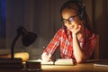 young woman student in headphones working on the computer at night