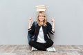 Young woman student holding books on head and pointing Royalty Free Stock Photo