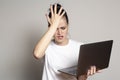 Young woman student looks at her laptop, she is confused and worried about solving a problem, holds her palm on her forehead and Royalty Free Stock Photo