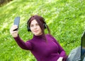 Young woman student in the park listening music with headphones take a selfie Royalty Free Stock Photo