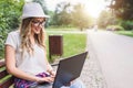 Young woman student sitting on park bench working on laptop computer Royalty Free Stock Photo