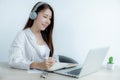 Young woman student taking notes watching laptop study online class video conference education elearning course from home Royalty Free Stock Photo