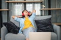 Young woman student wearing headphones is relaxing during long online classes, distance learning on the couch at home Royalty Free Stock Photo
