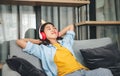 Young woman student wearing headphones is relaxing during long online classes, distance learning on the couch at home Royalty Free Stock Photo