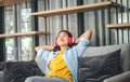 Young woman student wearing headphones is relaxing during long online classes, distance learning on the couch at home Royalty Free Stock Photo