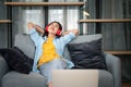 Young woman student wearing headphones is relaxing during long online classes, distance learning on the couch at home Royalty Free Stock Photo