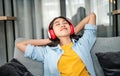 Young woman student wearing headphones is relaxing during long online classes, distance learning on the couch at home Royalty Free Stock Photo