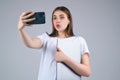 Young woman Student in white t-shirt holding phone and laptop, isolated over gray background. Student making video call Royalty Free Stock Photo