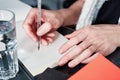 Young woman or student working and writing on paper notebook, using smart phone. Close up of woman`s hands making notes. Royalty Free Stock Photo