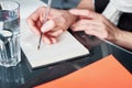 Young woman or student working and writing on paper notebook, using smart phone. Close up of woman`s hands making notes. Royalty Free Stock Photo