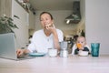 Young woman studying or working online at home while having breakfast with her baby on kitchen. Millennial mother on maternity Royalty Free Stock Photo