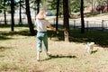 Young woman in stylish clothes walking in the park with her dog, rear view. Blonde girl and jack russell terrier