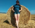 Outdoor fashion portrait of Stylish female in jeans suit posing on strawfield, bottom view. Royalty Free Stock Photo