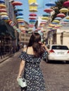 Young woman in stylish dress walking down the street alone.