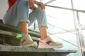 Young woman in stylish sneakers sitting on grey stairs, closeup
