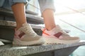 Young woman in stylish sneakers sitting on grey stairs, closeup