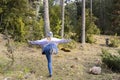 Young woman in stylish snow hat doing soldier one or angel yoga pose outdoor in nature forest park.Active fashion female in