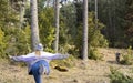 Young woman in stylish snow hat doing soldier one or angel yoga pose outdoor in nature forest park.Active fashion female in