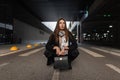 Young woman in stylish spring wear with silk vintage scarf with fashion leather handbag posing on the road outdoors. Cute girl Royalty Free Stock Photo